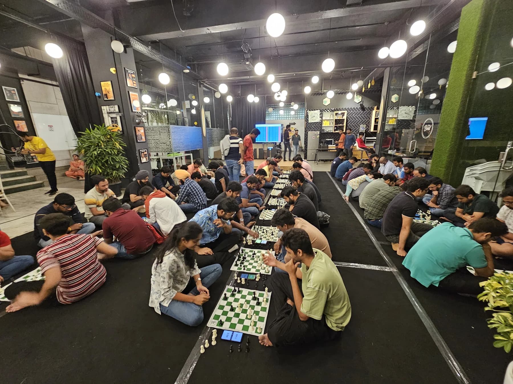 People seated in rows on the floor, playing chess at a club meetup in Bangalore.