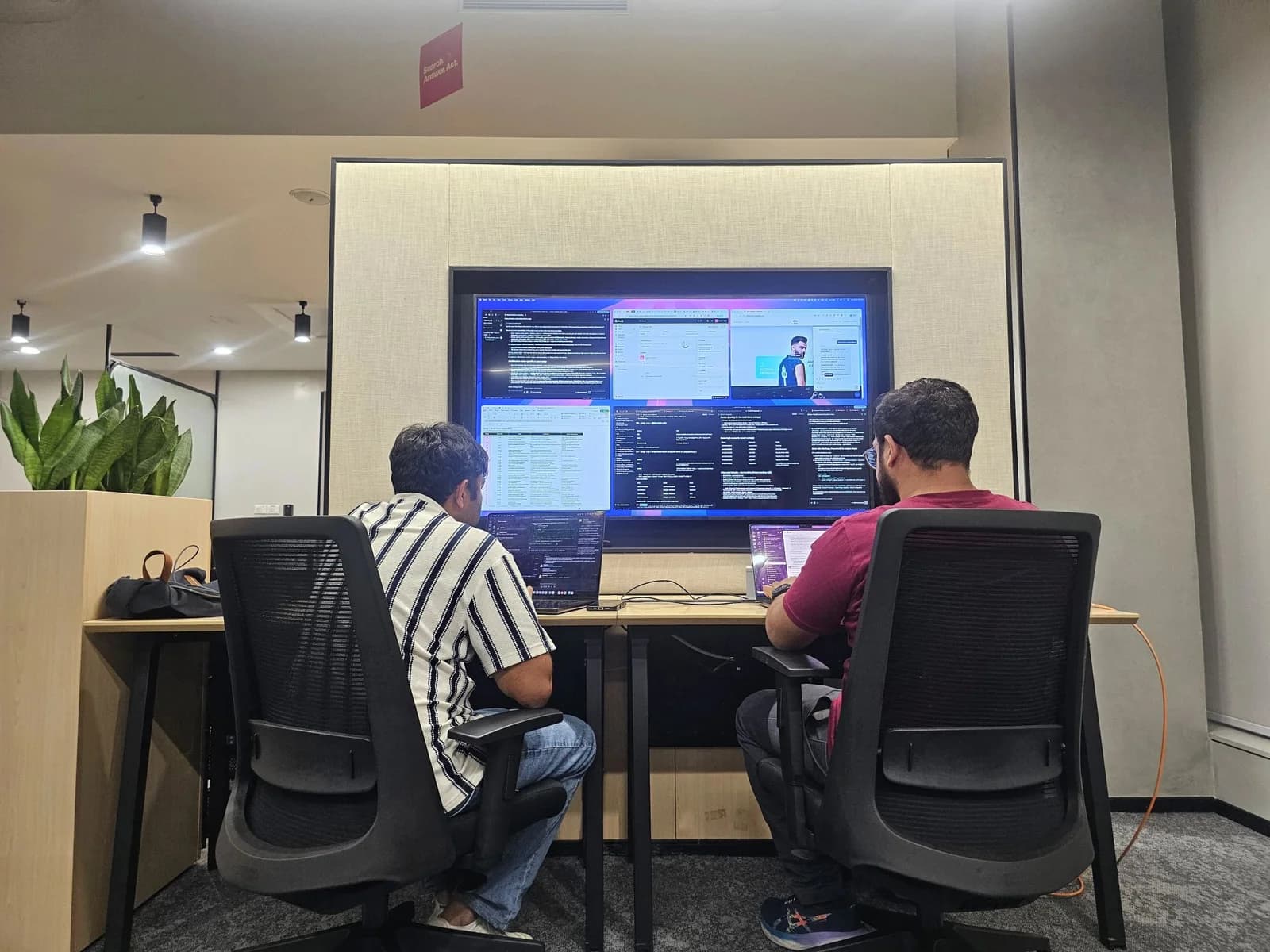 Two people working together at computer screens in an office.
