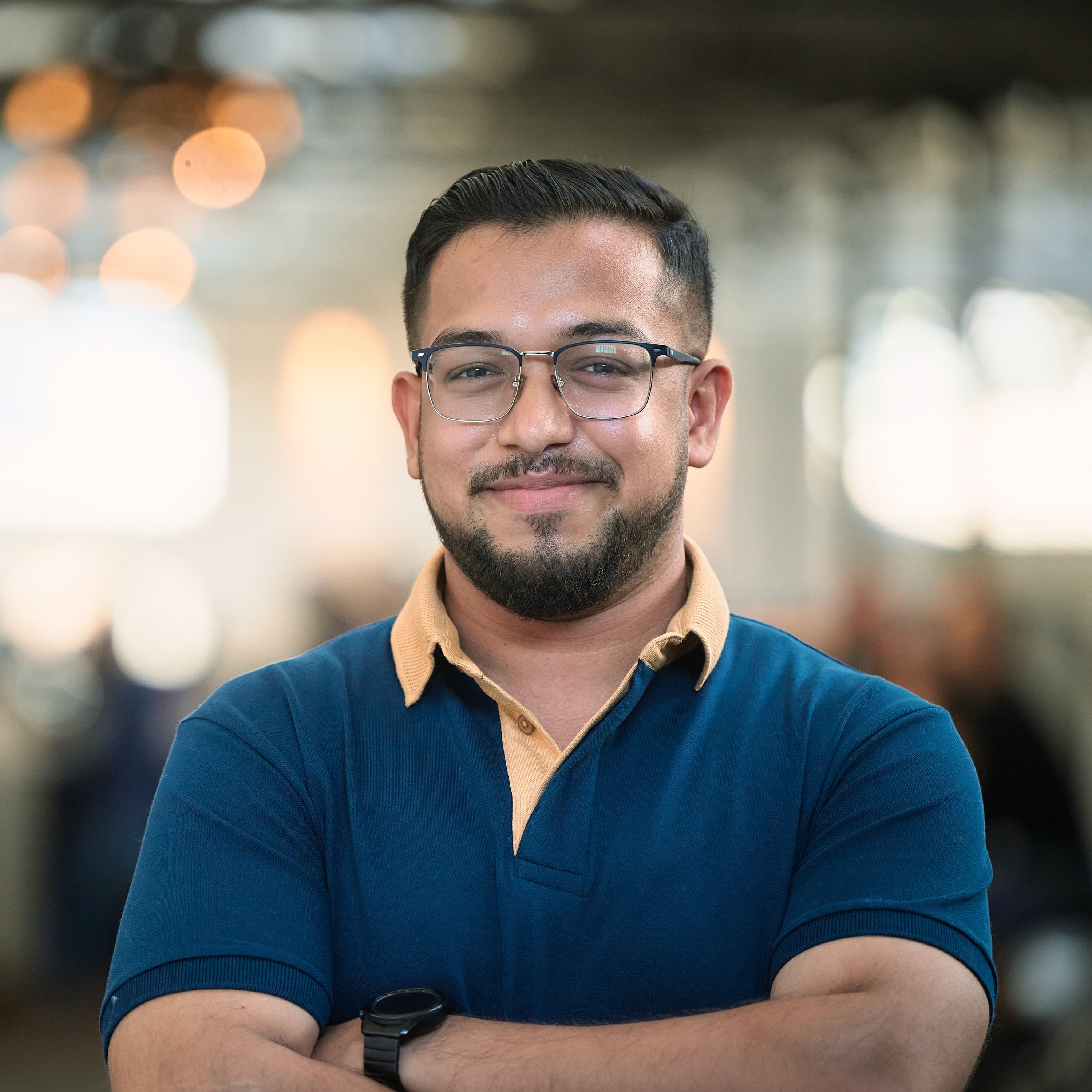 Ashish smiling with his arms folded, wearing a blue polo shirt at NDC Copenhagen.