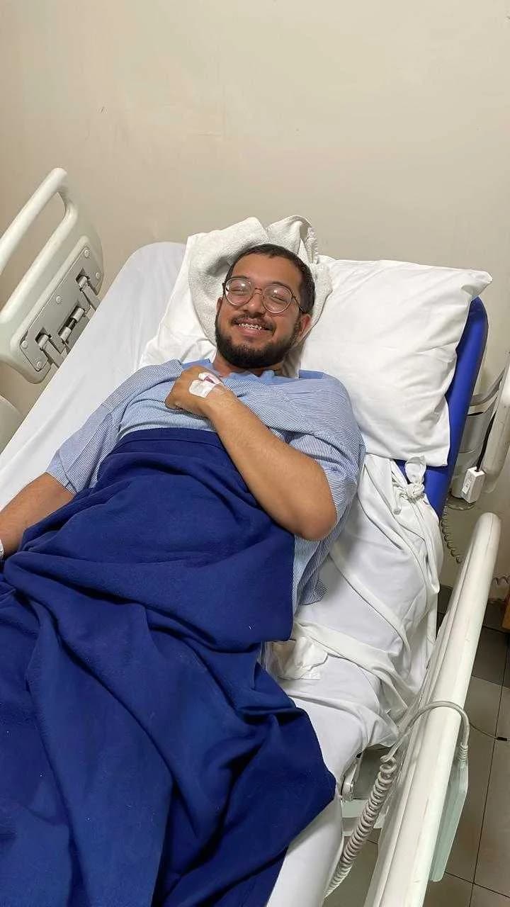 Ashish resting in a hospital bed, smiling at the camera.