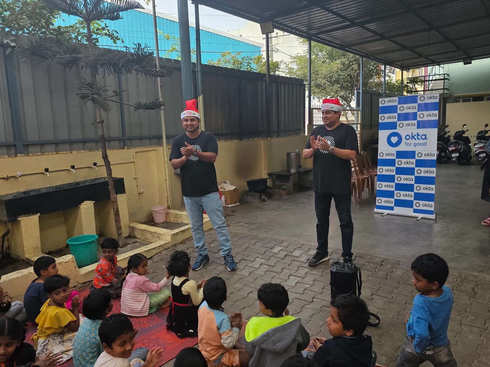 Okta volunteers leading a game, with children seated in rows at Jeevitha.