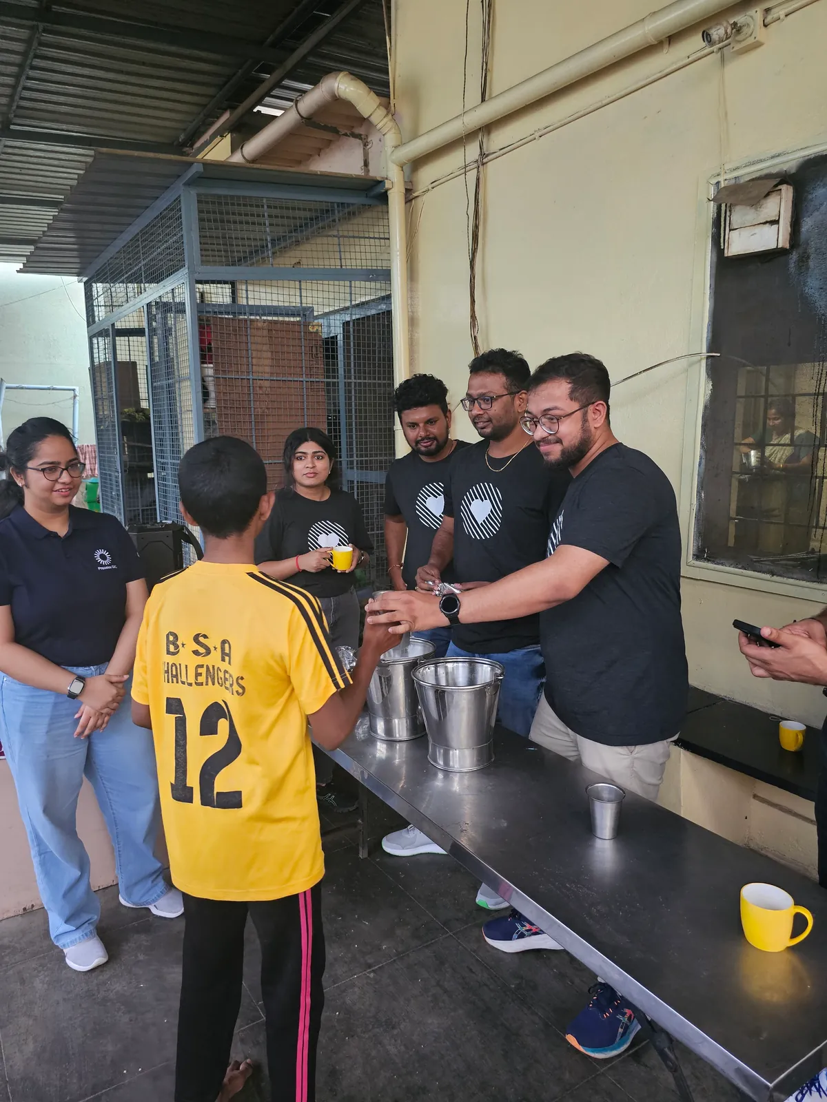 Ashish and other volunteers serving food from large pots at Jeevitha.