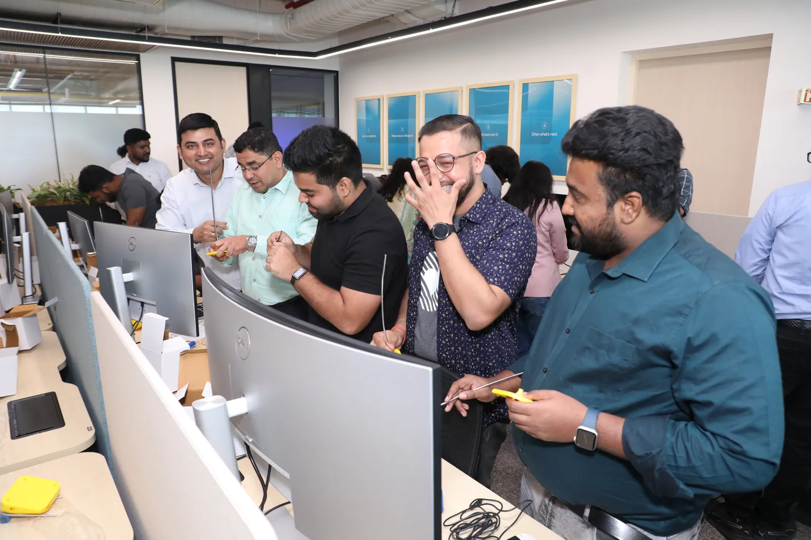 Ashish and colleagues assembling yellow solar lamps at desks in the Okta office.