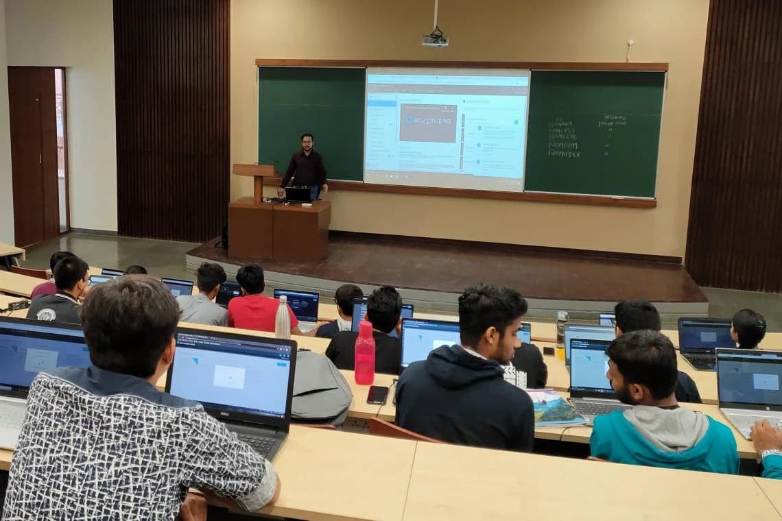 Ashish at the front of a lecture hall, with Quark workshop participants working on laptops.