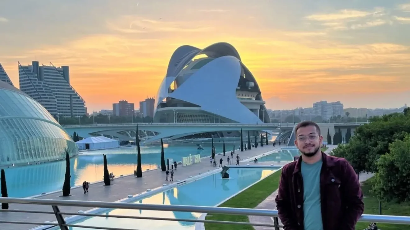 Ashish at the City of Arts and Sciences in Valencia, with futuristic white buildings and a sunset behind him.